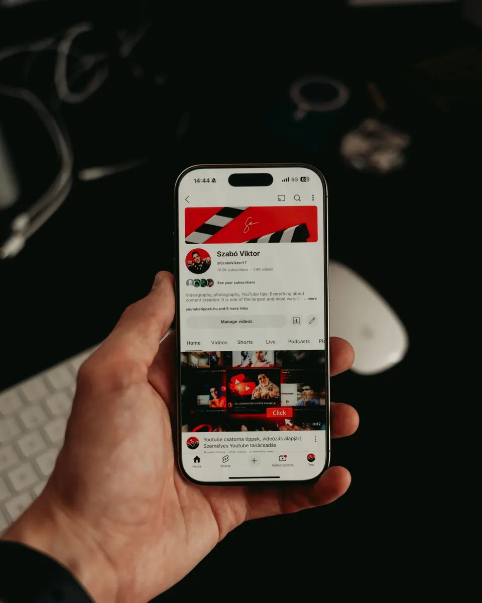Ruka drži mobitel s otvorenom društvenom mrežom na tamnoj podlozi